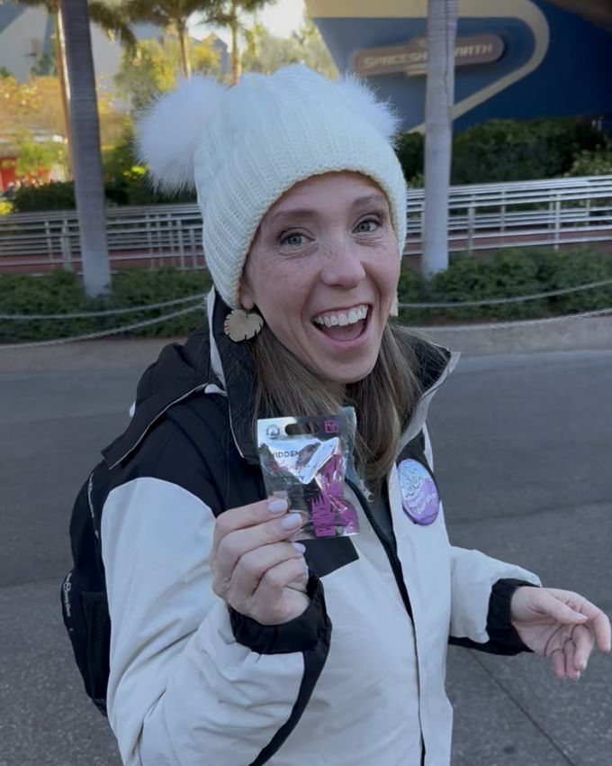 Lynne with a pin pouch outside Spaceship Earth on a chilly park morning